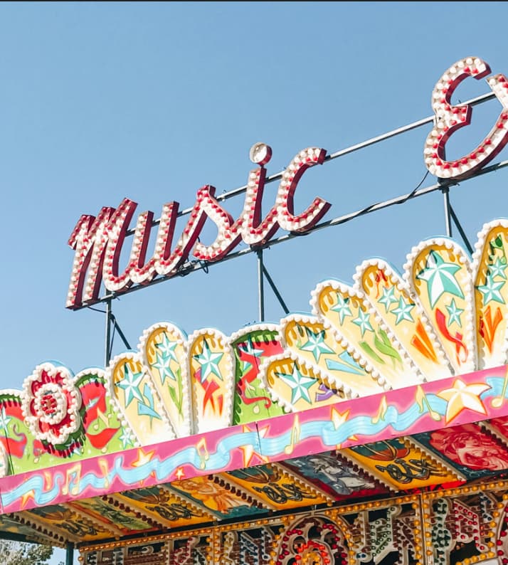 View of a fairground attraction sign with blue sky behind